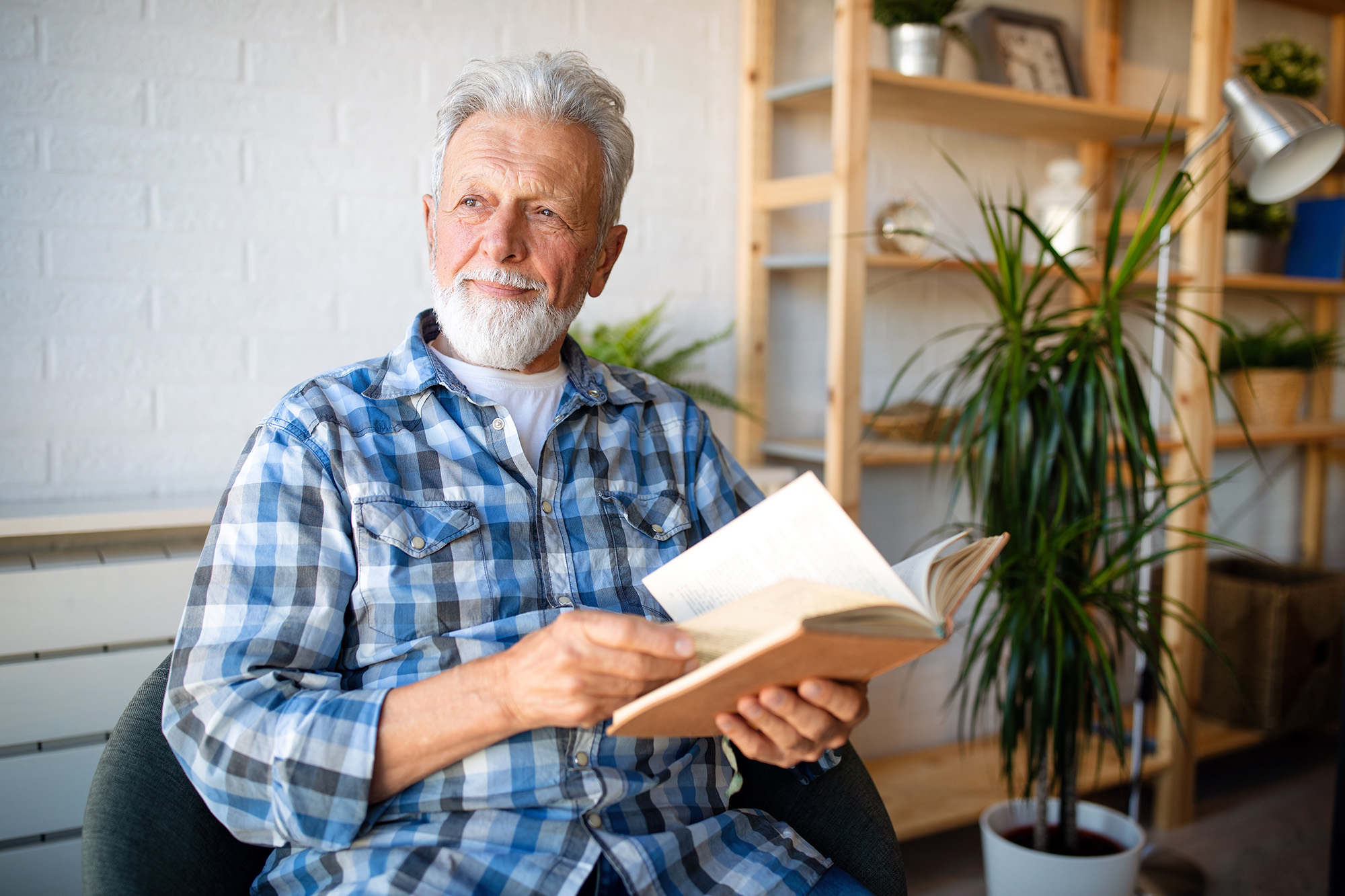 Happy senior man reading book at home